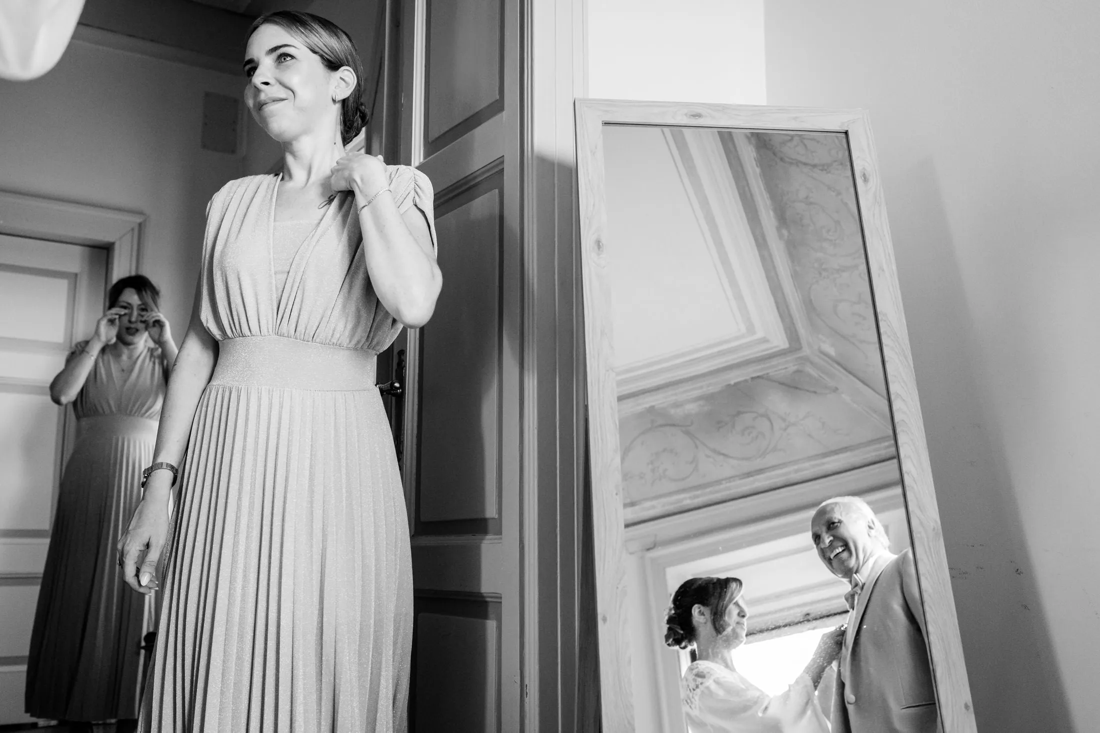 Home Page Simone Goglia 7 Damigella emozionata durante i preparativi della sposa, mentre la sposa e il papà si riflettono nello specchio
