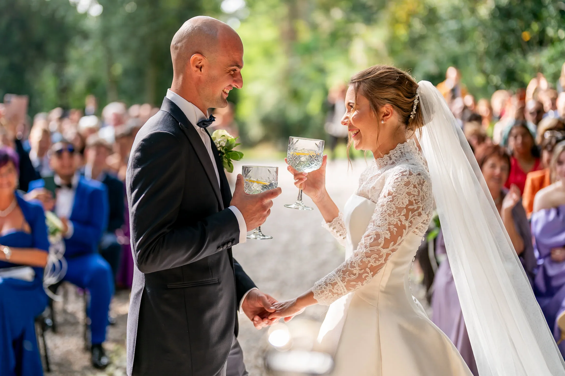 Home Page Simone Goglia 10 Bride and groom smiling and toasting in front of their guests during the ceremony