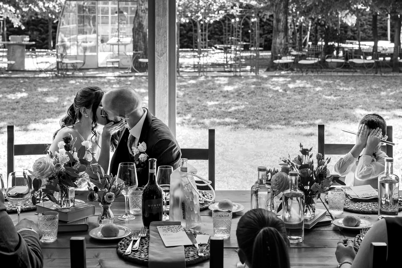 Reviews 9 The couple kiss at the table while a child covers his eyes, in black and white